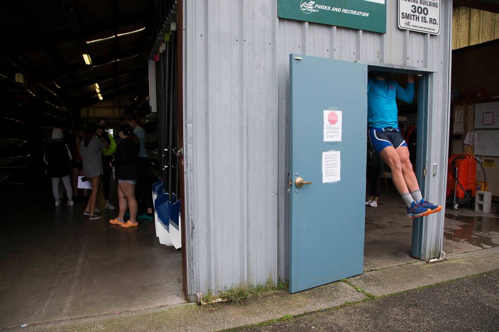 Owen Moody uses a doorway to do pull-ups as rowers with the Everett Rowing Association meet in the boathouse before heading out for practice. (Andy Bronson / The Herald)
