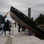 While rowers prep their sculls, the Everett Rowing Associations Hannah Swissa and Sarah Swisa lower a skiff into the water. (Andy Bronson / The Herald)