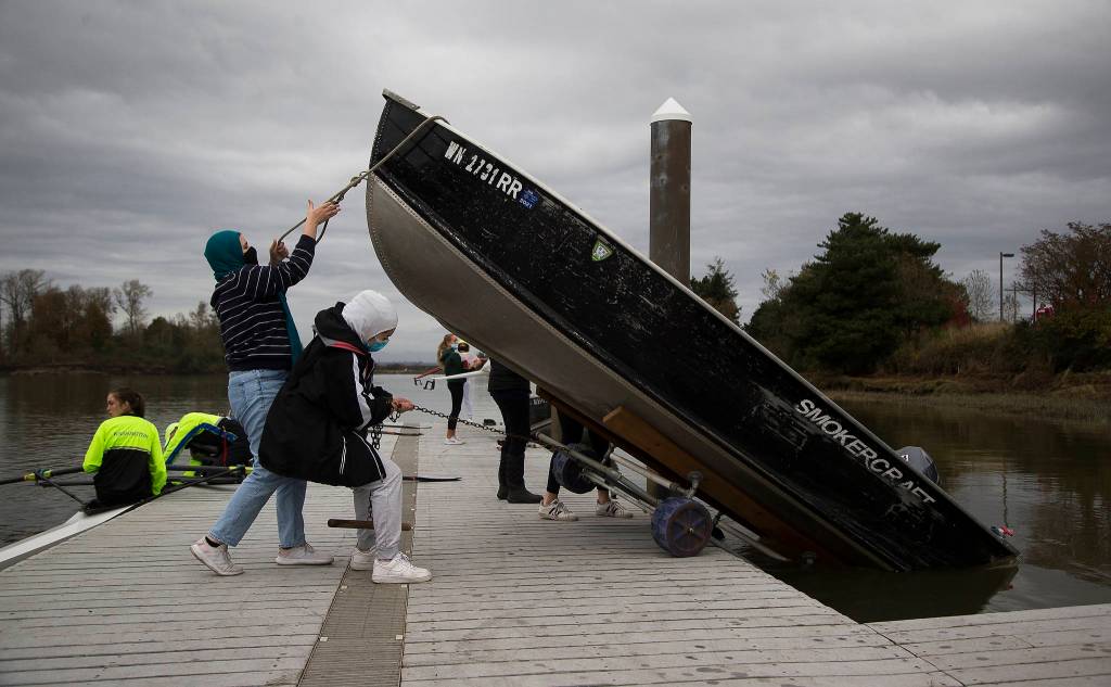 While rowers prep their sculls, the Everett Rowing Associations Hannah Swissa and Sarah Swisa lower a skiff into the water. (Andy Bronson / The Herald)