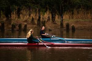 Aimelie Hovde-Girard, right, chats with Payton Wold as they row along the Snohomish River with the Everett Rowing Association on Monday, Oct. 19, 2020 in Everett, Washington. The rowers usually compete in teams of eight, but due to COVID-19, most row single sculls.  (Andy Bronson / The Herald)