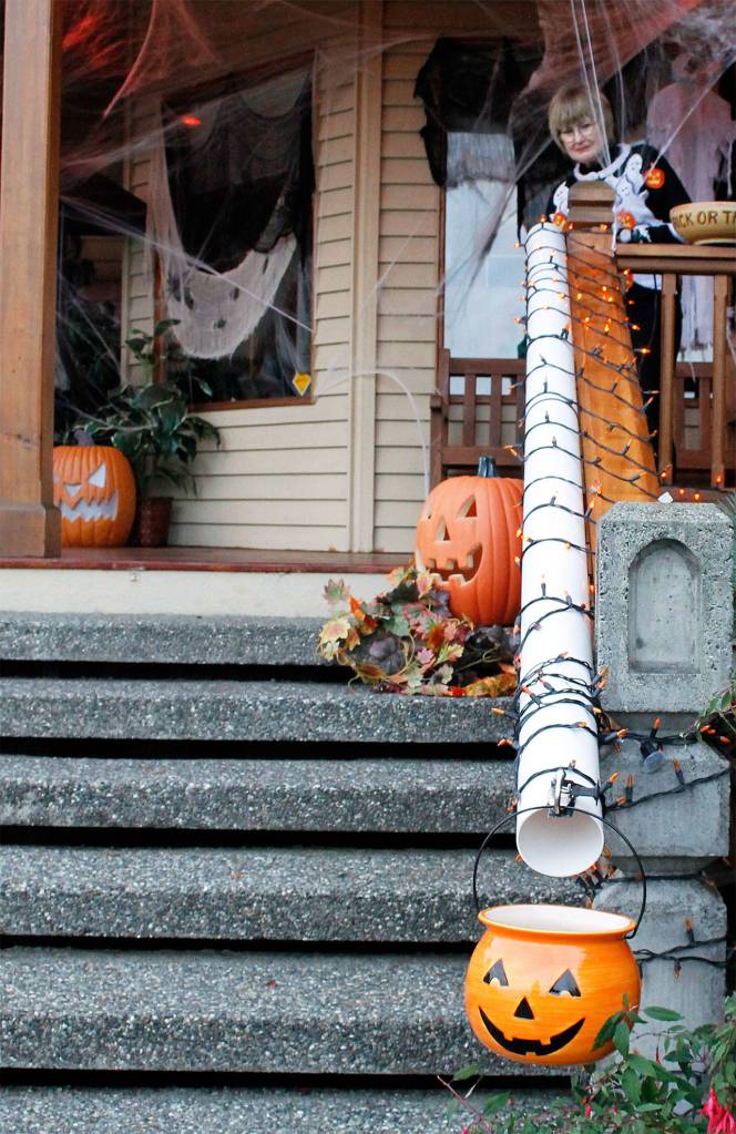 Micky Lacewell sends treats down a socially distant candy delivery pipe to her granddaughters. (Kira Erickson / Whidbey News Group)