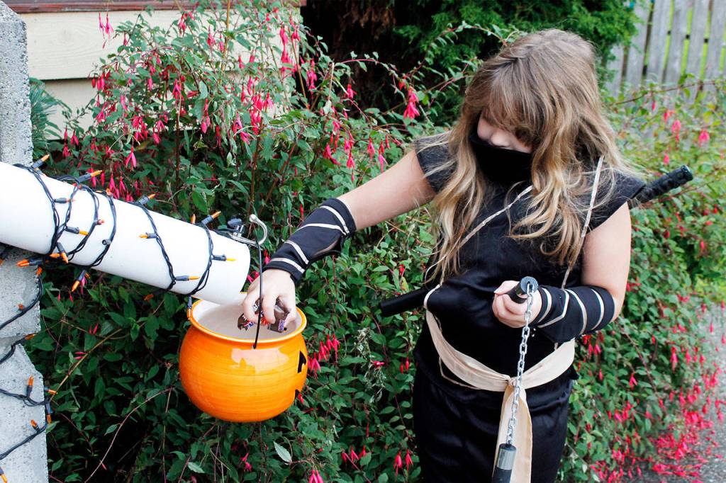 Lilah Babaidhan, 9, demonstrates how the candy chute outside her grandparents house will work. (Kira Erickson / Whidbey News Group)