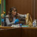 Jana Smith places the boot worn by her sister, Jody Loomis, back into an evidence bag while testifying Wednesday in Everett. (Olivia Vanni / The Herald)