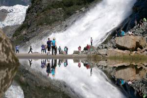 FILE - In this July 31, 2013, file photo, tourists visiting the Mendenhall Glacier in the Tongass National Forest are reflected in a pool of water as they make their way to Nugget Falls in Juneau, Alaska. The U.S. Forest Service announced plans Wednesday, Oct. 28, 2020, to lift restrictions on road building and logging in Tongass National Forest, a largely pristine rainforest in southeast Alaska that provides habitat for wolves, bears and salmon. Conservation groups vowed to fight the decision. (AP Photo/Charles Rex Arbogast, File)