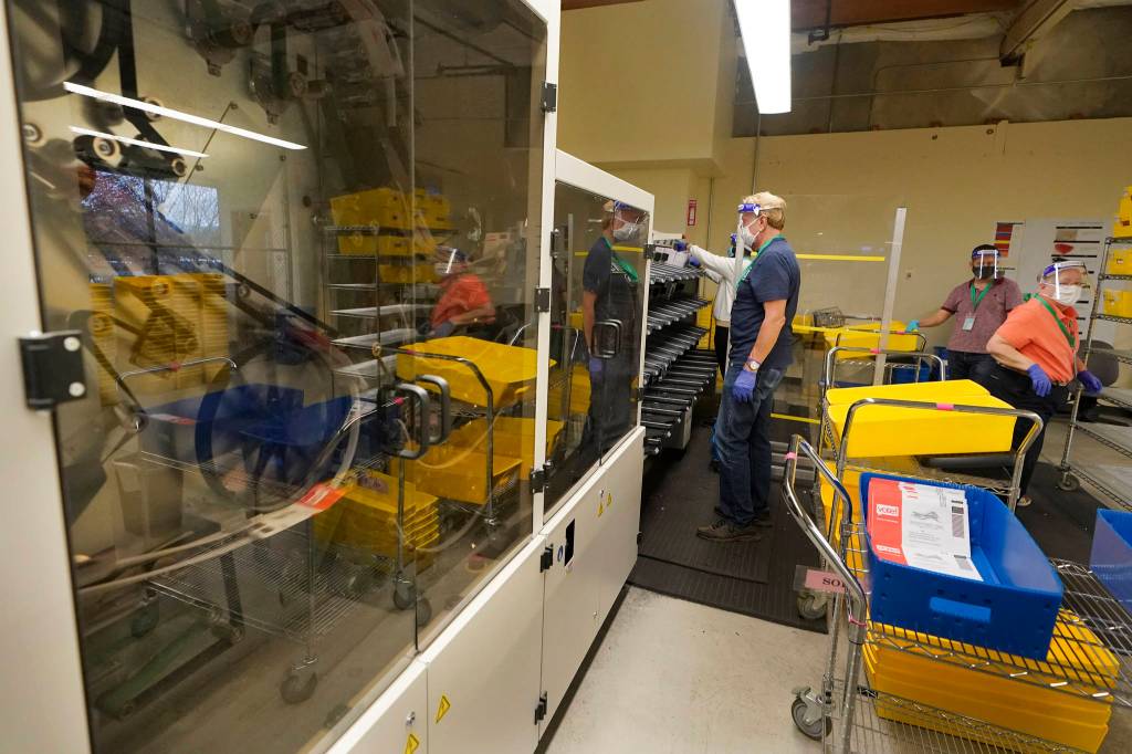FILE - Workers at the King County election headquarters in Renton, Wash., process ballots in this Oct. 23, 2020 file photo. A record number of voters in Washington have already returned their ballots as of Friday, Oct. 30, 2020, and other voters have until 8 p.m. Tuesday, Nov. 3, 2020 to drop off or mail their ballots or vote in person. (AP Photo/Ted S. Warren, File)