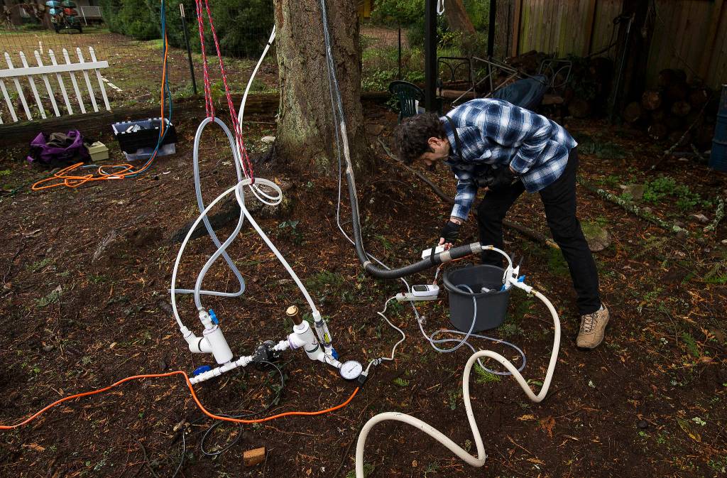 Scott Greeley adjusts a temperature gauge on his energy-saving distillation system, which hangs 43 feet up in a tree in Edmonds. (Andy Bronson / The Herald)