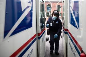 FILE - In this May 6, 2020, photo, United States Postal Service carrier Henrietta Dixon gets into her truck to deliver mail in Philadelphia.  Officials from six states and the District of Columbia are in court Thursday, Sept. 24,  to ask a federal judge to halt alleged slowdowns at the U.S. Postal Service that they say threaten the upcoming presidential election(AP Photo/Matt Rourke, File)
