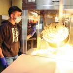 Jack Eccleshall makes popcorn at the theater for sale while it was still closed. (Kevin Clark / The Herald)