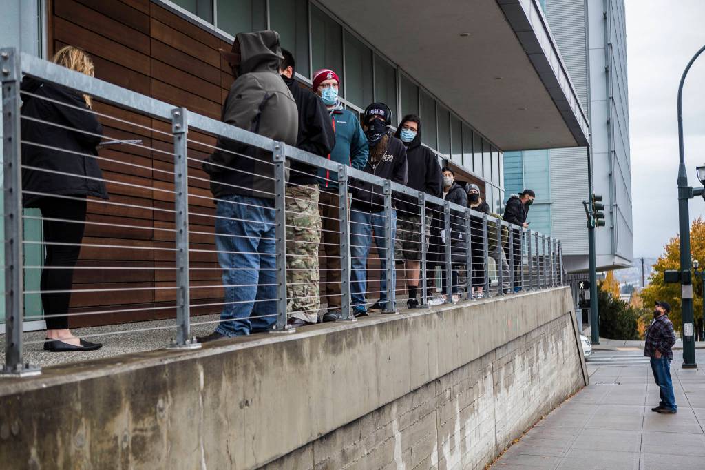 People line up outside of the County Public Meeting Room to turn in ballots, register to vote and get help on Tuesday in Everett. (Olivia Vanni / The Herald)