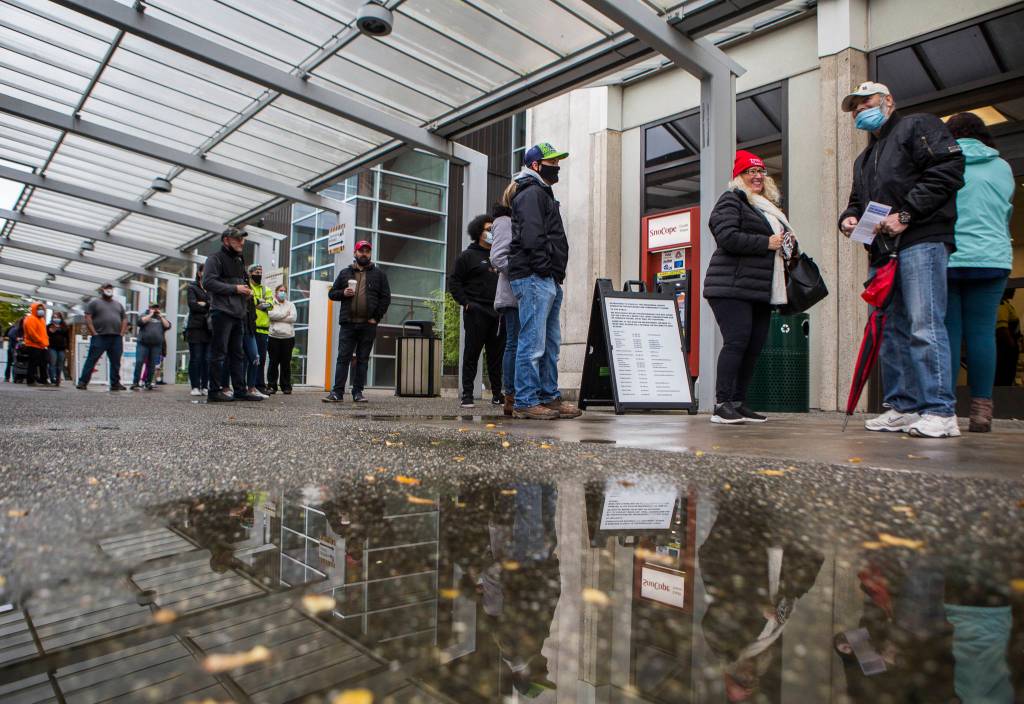 People wait in line outside the Snohomish County auditors office to turn in ballots, register to vote and get help on Tuesday in Everett. (Olivia Vanni / The Herald)