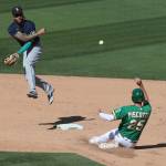 The Mariners J.P. Crawford (left) throws to first base as the Athletics Stephen Piscotty slides into second on a double play during the seventh inning of a game on Sept. 26, 2020, in Oakland, Calif. (AP Photo/Jed Jacobsohn)