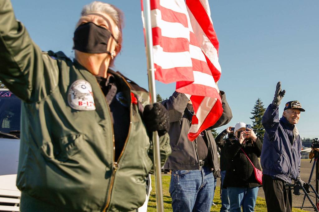 Marylee Edwards (left) and Art Unruh wave to a vintage warplane flyover Sunday afternoon at the Arlington Airport. (Kevin Clark / The Herald)