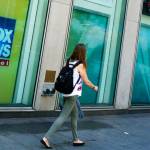 FILE- People pass the News Corporation headquarters building and Fox News studios in New York on Aug. 1, 2017. Several Fox News Channel executives and on-air personalities were exposed last week to a person on a private plane who later tested positive for COVID-19. It has led to some restrictions at the network. Anchor Bret Baier said Monday that he's tested negative three times in the wake of the flight and will be doing his nightly news show from home this week. (AP Photo/Richard Drew, File)