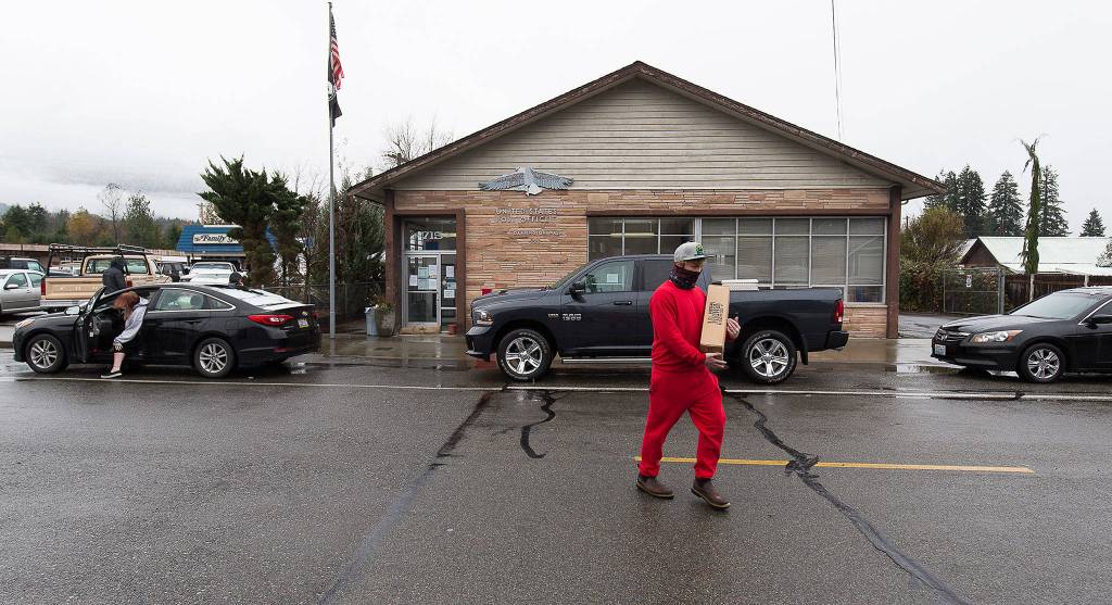 Dustin Grant carries a package after picking it up outside the closed Darrington Post Office on Tuesday. (Andy Bronson / The Herald)
