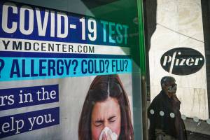A bus stop ad for COVID-19 testing is shown outside Pfizer world headquarters in New York on Monday Nov. 9, 2020. Pfizer says an early peek at its vaccine data suggests the shots may be 90% effective at preventing COVID-19, but it doesn't mean a vaccine is imminent. (AP Photo/Bebeto Matthews)