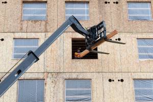 A worker unloads two-by-fours from a forklift as construction continues on the new Compass Health project on 33rd Street on Wednesday, Nov. 18, 2020 in Everett, Washington. Compass Health got a $1 million grant from Sunderland Foundation, a boost to its Broadway Redevelopment Project in Everett. First phase is a five-story, 82-unit apartment building for supportive housing, second phase is a behavioral health services building to replace the 70-year-old brick building on Broadway. (Andy Bronson / The Herald)