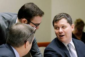 Grocery Manufacturers Association lawyer Matthew Gardner, right, talks with others before making arguments in a case alleging that the food industry group violated state campaign disclosure laws in opposing a 2013 food labeling initiative, Friday, Feb. 19, 2016, in Olympia, Wash. Washington Attorney General Bob Ferguson sued the Grocery Manufacturers Association in October 2013, saying it collected money from member companies to defeat Initiative 522 but engaged in a scheme to shield those contributions from public scrutiny. Voters narrowly rejected the initiative, which would have required labeling of genetically modified foods. (AP Photo/Elaine Thompson)