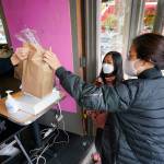 Customer Kyung Kim, right, and her daughter Alexa Oh, 9, are handed their purchased baked goods through an open door by cashier Donna Te as they maintain social distance and wear masks Thursday, Nov. 12, 2020, in Seattle. Washington state and county health officials have warned of a spike in coronavirus cases across the state, and pleaded with the public to take the pandemic more seriously heading into the winter holidays. (AP Photo/Elaine Thompson)