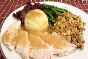 Photo of white meat turkey with mashed potatoes, gravy, cranberry sauce, green beans and stuffing served for thanksgiving.