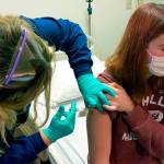 In this photo provided by Cincinnati Children’s Hospital Medical Center, clinical research coordinator Tammy Lewis-McCauley administers an injection to Katelyn Evans, a trial participant, as part of the hospital’s clinical trial of Pfizer's COVID-19 vaccine at Cincinnati Children’s Hospital Medical Center on Wednesday, Oct. 14, 2020. (Cincinnati Children’s Hospital Medical Center via AP)