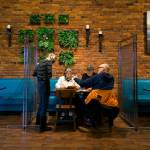 Server Kelly King talks with diners Suzan Nettleship, Bill Zama and Rodger Scheibner as they enjoy a last restaurant meal indoors at Sol Food on Monday in Everett before restrictions are in place. (Andy Bronson / The Herald)