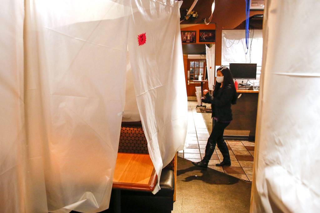 A customer makes her way to a pod, booths draped sheeting, at AFK Tavern in Everett on Nov. 15. The revered geek bar is closing after 10 years due to the lease being up and the impact of COVID-19. (Kevin Clark / The Herald)