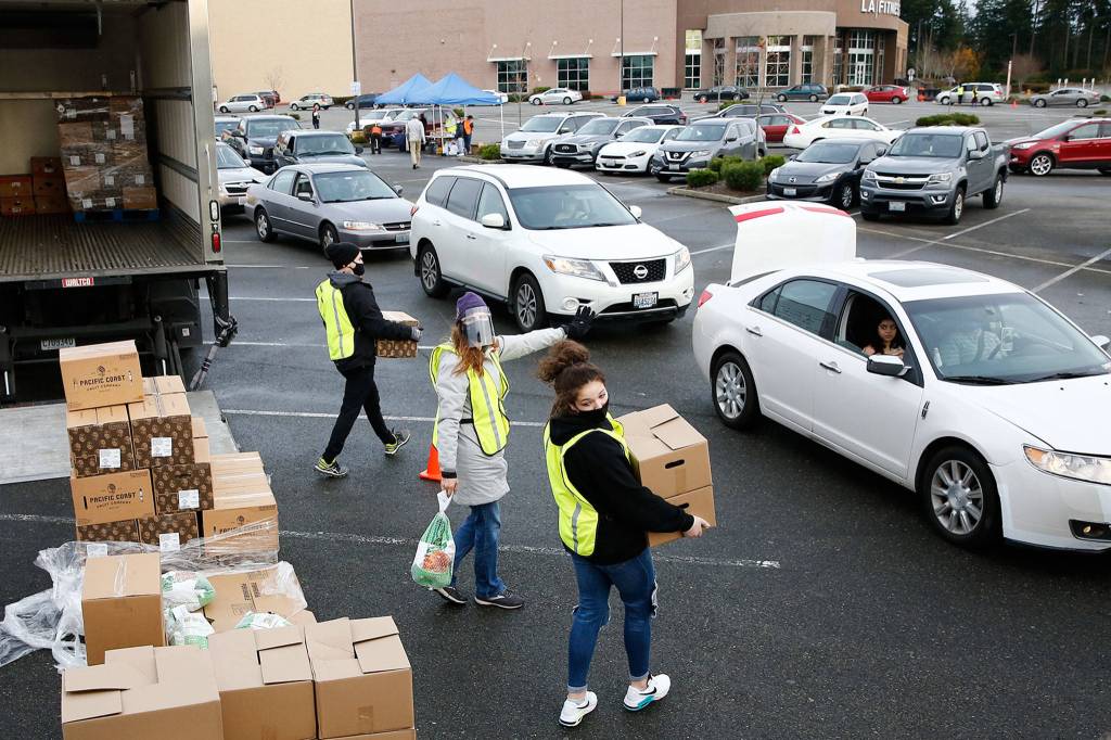 Volunteers of America and Farmer Frog load food stuffs Friday during a drive-thru distribution at Everett Mall. (Kevin Clark / The Herald)