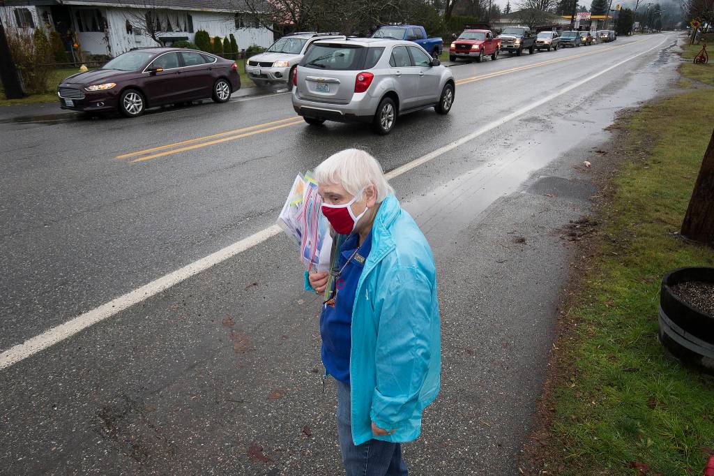 North County Family Services volunteer Mary Requa waits to hand out surveys for drivers waiting in line for a drive-through event for families in need called the Colors of Fall at the Darrington Food Bank on Monday. (Andy Bronson / The Herald)