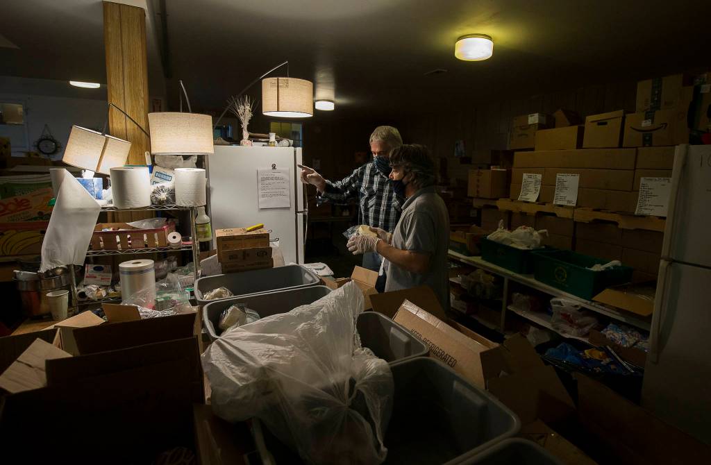 Hugh Kahn and Steve Brown (right) organize frozen items for a drive-through event for families in need called the Colors of Fall at the Darrington Food Bank on Monday. (Andy Bronson / The Herald)