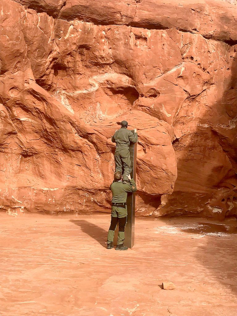 Utah state workers inspect a metal monolith in the ground in a remote area of red rock Nov. 18 in Utah. The mysterious silver monolith found in the Utah desert has disappeared less than 10 days after it was spotted by wildlife biologists performing a helicopter survey of bighorn sheep, federal officials and witnesses said. The Bureau of Land Management said it had received credible reports that the three-sided stainless steel structure was removed on Nov. 27. (Utah Department of Public Safety via AP, File)
