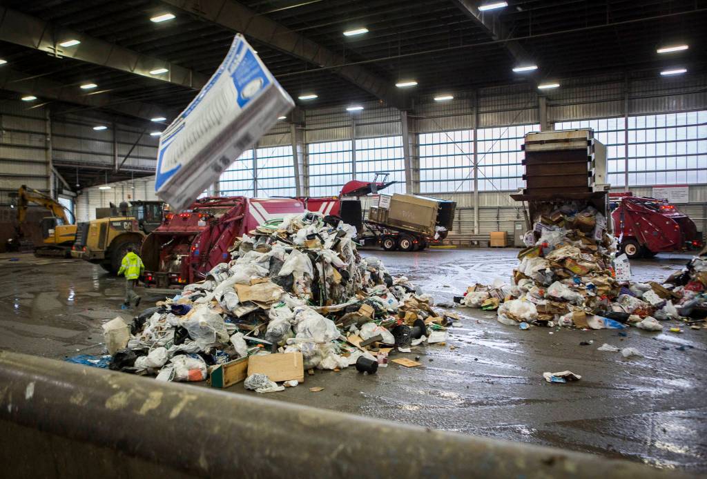 Garbage trucks dump trash onto the tipping floor at the Airport Road Recycling & Transfer Station on Nov. 24 in Everett. (Olivia Vanni / The Herald)