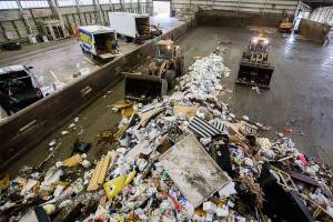 Front loaders push trash forward into one of the compactors at the Airport Road Recycling & Transfer Station on Tuesday, Nov. 24, 2020 in Everett, Wa. (Olivia Vanni / The Herald)