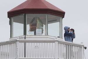 From the Mukilteo lighthouse, Michelle Wainstein watches for marine mammals before pile driving work begins on the new Mukilteo Ferry Terminal on Tuesday, Dec. 15, 2020 in Mukilteo, Washington. Manson Construction, the marine contractor on the ferry terminal project, is required to have monitors stand watch for marine mammals while crews do pile driving, typically several days a month. (Andy Bronson / The Herald)