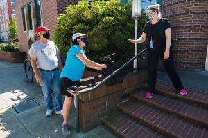 Leslie Bringedahl grabs a bag containing books she and her husband Mark ordered after Circulation Manager Carol  puts them down on a wall during curbside pickup at the Everett Public Library on Wednesday, June 17, 2020 in Everett, Wa.(Andy Bronson / The Herald)