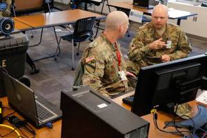 FILE - In this Tuesday, March 31, 2020, file photo, Washington Army and Air National Guard soldiers confer in an operations room at Camp Murray, Wash. The state of Washington is calling in the National Guard to help process unemployment benefit claims as officials grapple with a backlog caused in part by a fraud ring that stole more than half a billion dollars in aid, officials said Thursday, June 11, 2020. (AP Photo/Ted S. Warren,File)