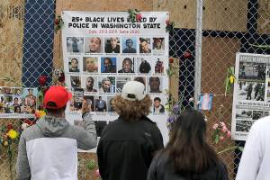 Visitors view photos of people who were killed by police in Washington State and elsewhere, Tuesday, June 16, 2020, inside what has been named the Capitol Hill Occupied Protest zone in Seattle. Police have pulled back from a part of the city's Capitol Hill neighborhood near the department's East Precinct after recent clashes with people protesting the death of George Floyd in Minneapolis. (AP Photo/Ted S. Warren)