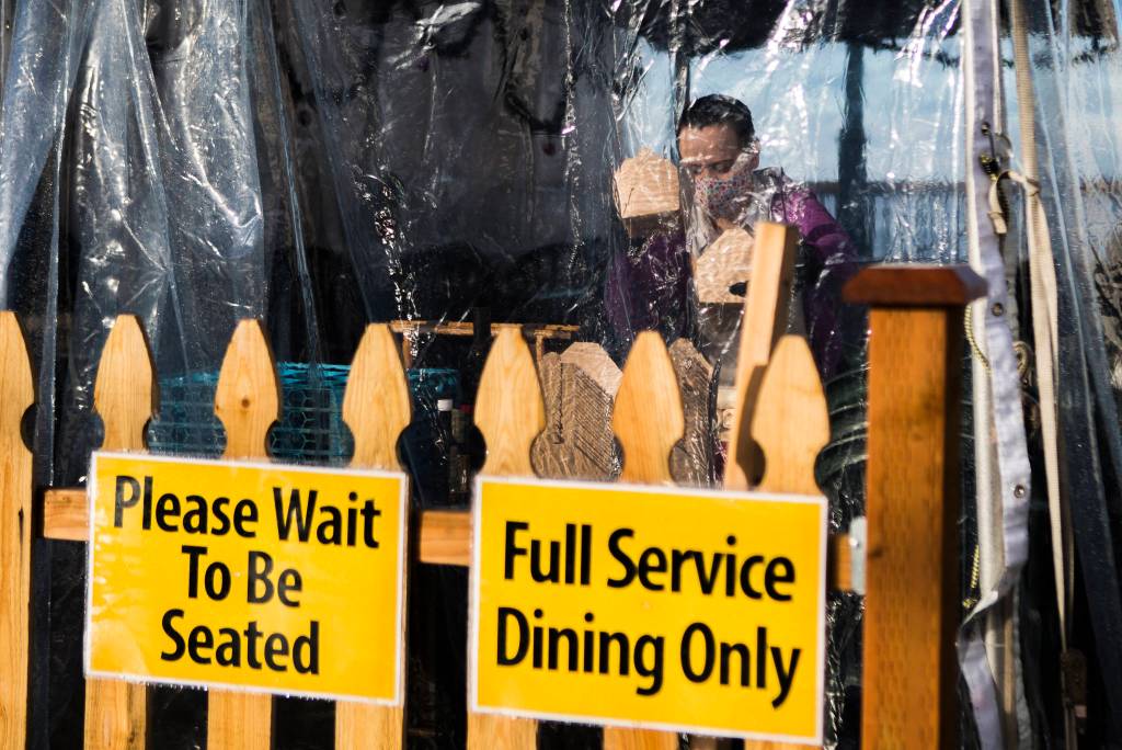 A waiter at Ivars packages food to go inside the outdoor tent in Mukilteo on Wednesday. (Olivia Vanni / The Herald)