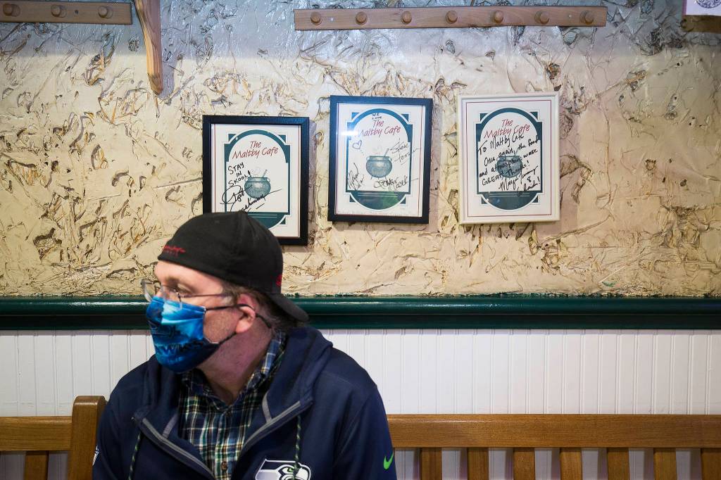 Below celebrity-signed logos, Robert Ferguson waits for his takeout order at the Maltby Cafe on Thursday. (Andy Bronson / The Herald)