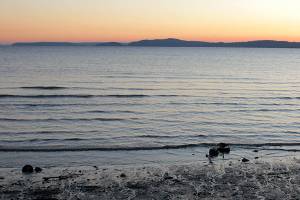 In this image taken Jan. 16, 2013, two people walk the beach at Discovery Park in Seattle. At 534 acres, Discovery Park is the largest park in the city and it features seaside bluffs, views of the Puget Sound, trails, a light house and a beach.  (AP Photo/Manuel Valdes )