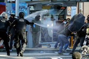 FILE - In this July 25, 2020, file photo, police pepper spray protesters, near Seattle Central College in Seattle, during a march and protest in support of Black Lives Matter. Washington state lawmakers and activists are setting an ambitious agenda for police reform in the upcoming legislative session. They say they hope to make it easier to decertify officers for misconduct, to bar the use of police dogs to make arrests, and to create an independent statewide agency to investigate police killings. (AP Photo/Ted S. Warren, File)