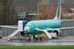 Workers stand near a Boeing 737 Max airplane parked at Renton Municipal Airport, Wednesday, Nov. 18, 2020, next to the Boeing assembly facility in Renton, Wash. where 737 Max airplanes are made. After nearly two years and a pair of deadly crashes, the U.S. Federal Aviation Administration announced Wednesday that the 737 Max has been cleared for flight after regulators around the world grounded the Max in March 2019, after the crash of an Ethiopian Airlines jet. (AP Photo/Ted S. Warren)