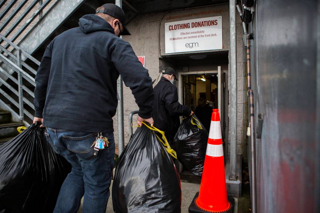 Bags filled with coats and other donations from Tonja Jones are carried inside the Everett Gospel Mission on Dec. 10. (Olivia Vanni / The Herald)