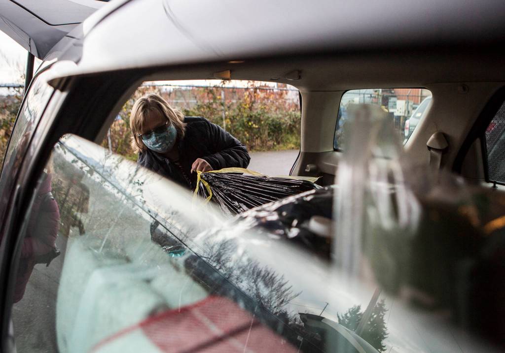 Tonja Jones pulls out bags of coats from one of the two cars she filled outside the Everett Gospel Mission on Dec. 10. (Olivia Vanni / The Herald)