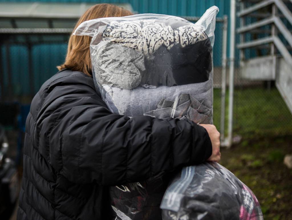 Tonja Jones carries bags of donated coats into the Everett Gospel Mission on Dec. 10. (Olivia Vanni / The Herald)