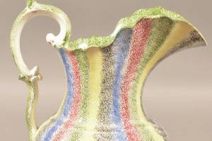 This 11-inch-high antique rainbow spatterware water picture with bands in five different colors sold for more than $5,000 at a Conestoga auction this year. Notice the double G-scroll handle, an added value feature. (Cowles Syndicate Inc.)