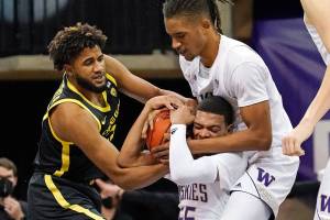 Oregon's LJ Figueroa, left, struggles for control of the ball with Washington's Quade Green, bottom right, and Hameir Wright during the first half of an NCAA college basketball game Saturday, Dec. 12, 2020, in Seattle. (AP Photo/Elaine Thompson)