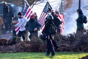Supporters of President Donald Trump and antifa supporters clashed with Washington state police on the state Capitol Campus in Olympia, Wash., Saturday, Dec. 12, 2020. Police in Olympia declared a riot early Saturday afternoon and arrested at least one person as groups with different points of view held simultaneous protests. (The Olympian via AP)