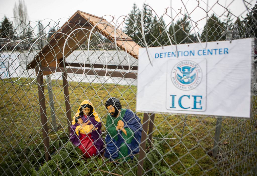 An ICE Detention Center sign hangs on the chain-link fence surrounding the Nativity scene in front of Edmonds Lutheran Church. (Olivia Vanni / The Herald)