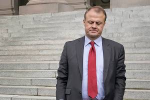 Initiative promoter Tim Eyman holds a T-shirt from long-running campaign for $30 car tabs as he waits to talk to reporters, Thursday, Oct. 15, 2020, at the Capitol in Olympia, Wash. The Washington Supreme Court on Thursday unanimously struck down Eyman's Initiative 976, a measure that would have steeply discounted the price of car registrations at $30 while gutting transportation budgets across Washington state. (AP Photo/Ted S. Warren)