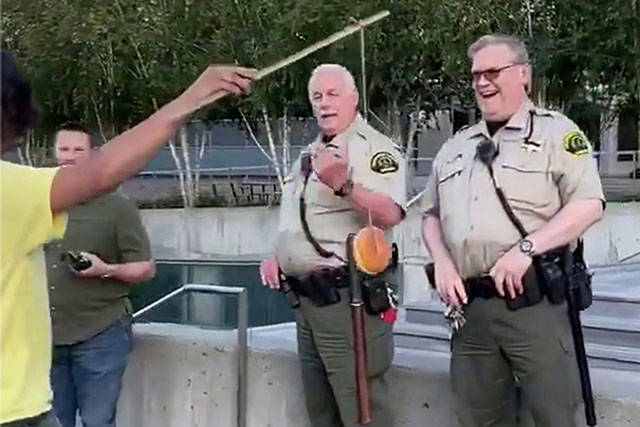 A man dangles a donut in front of sheriffs court marshals. (Screen grab from video courtesy of Bennett Haselton)